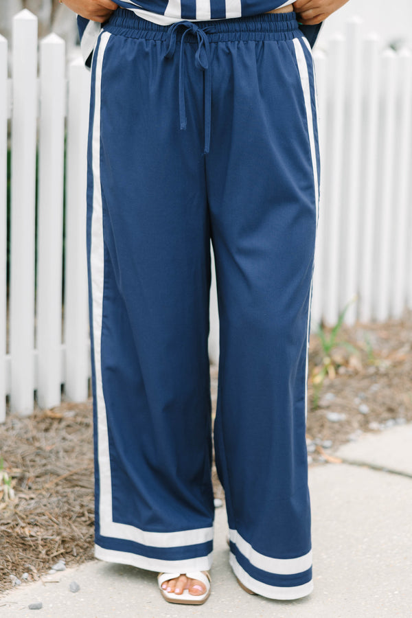 Chic Soul plus size clothing, navy blue long flowy pants with elastic waistband and drawstrings with vertical white lines down the outer sides of the pants that lead into horizontal white lines bordering the bottom of the pants