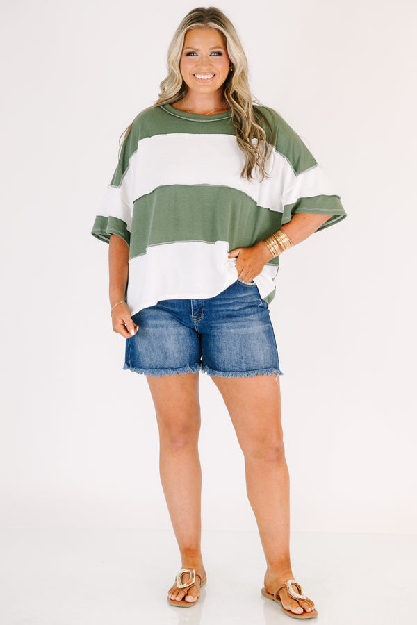 Plus size woman in a light olive and white striped oversized tee with raw edge seam details.