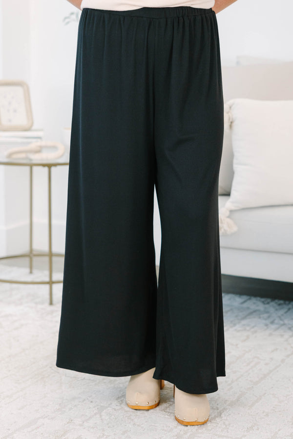 Plus size black flowy palazzo pants with a high-rise elastic waistband and soft ribbed fabric.