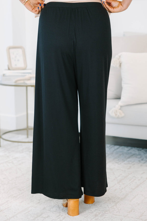 Plus size black flowy palazzo pants with a high-rise elastic waistband and soft ribbed fabric.