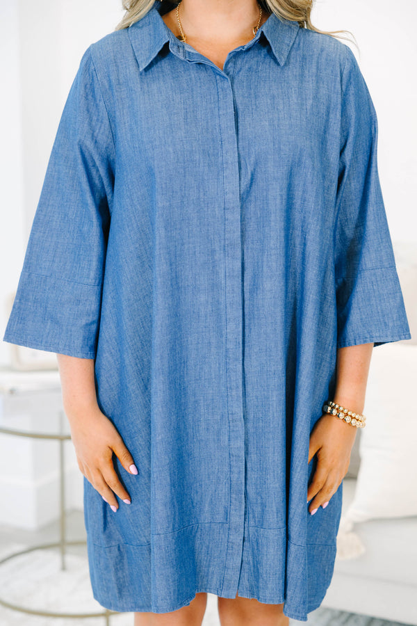 Plus size blue chambray shirt dress with a flowy fit, button placket, and three-quarter sleeves.
