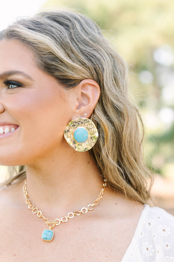 Large hammered gold disc earrings with a round turquoise stone center.