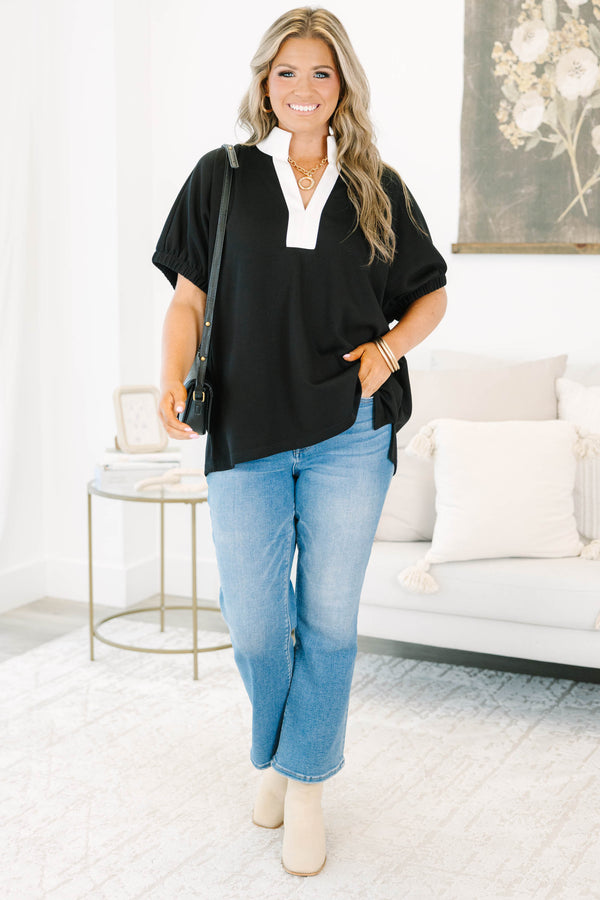 Plus size black top with a white v-neck collar, flowy fit, and short puff sleeves.