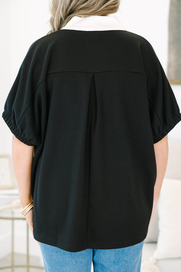 Plus size black top with a white v-neck collar, flowy fit, and short puff sleeves.