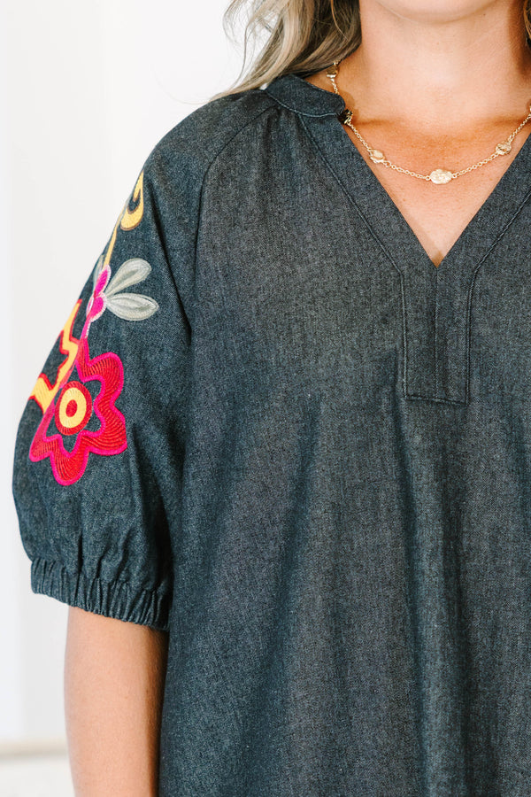 Plus Size black denim top with a v-neckline and colorful floral embroidery on puff sleeves.