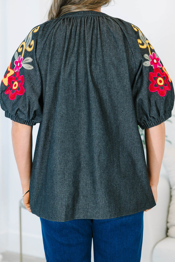 Plus Size black denim top with a v-neckline and colorful floral embroidery on puff sleeves.