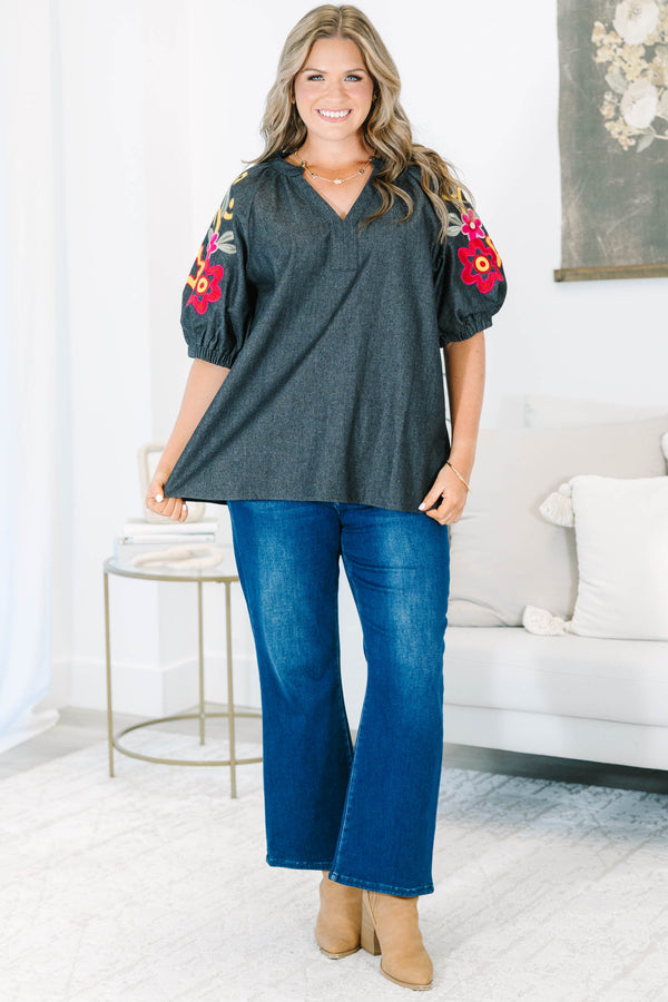 Plus Size black denim top with a v-neckline and colorful floral embroidery on puff sleeves.