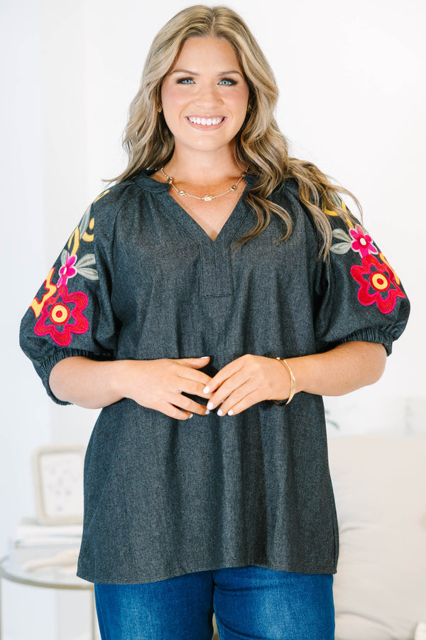 Plus Size black denim top with a v-neckline and colorful floral embroidery on puff sleeves.