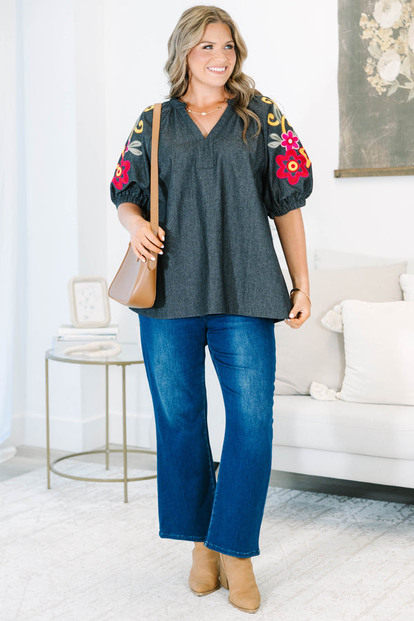 Plus Size black denim top with a v-neckline and colorful floral embroidery on puff sleeves.