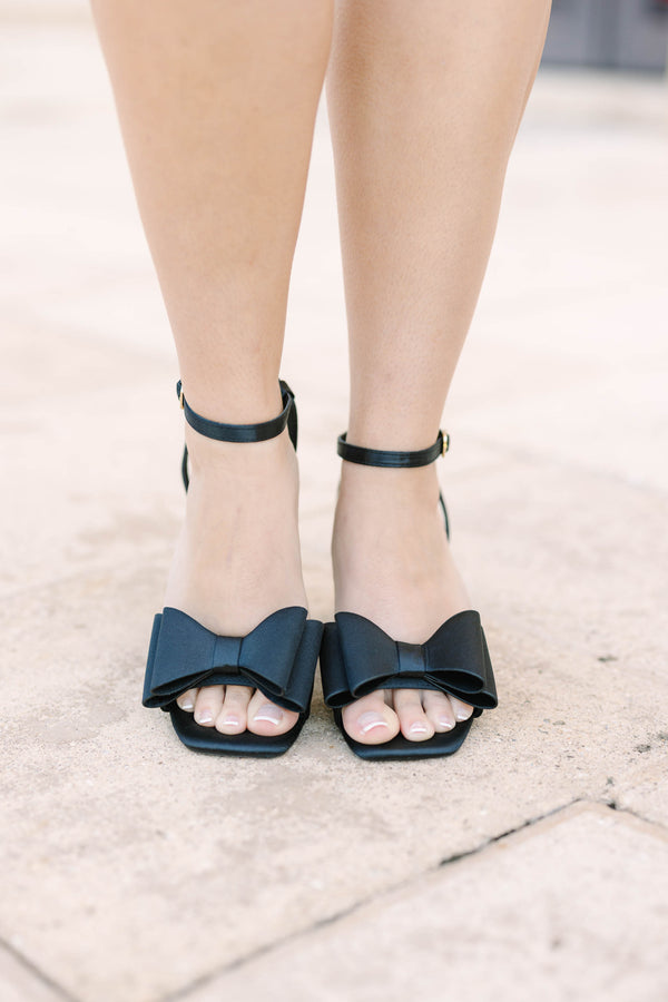 Plus size black satin block heels with a bow detail and adjustable ankle strap.