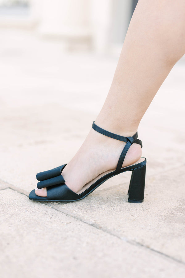 Plus size black satin block heels with a bow detail and adjustable ankle strap.