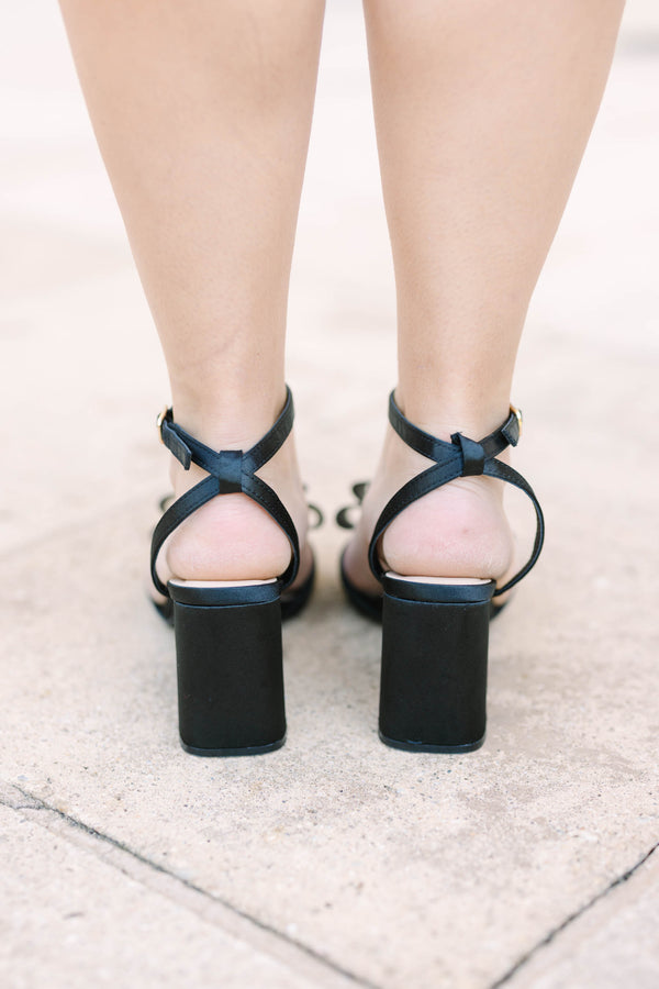 Plus size black satin block heels with a bow detail and adjustable ankle strap.