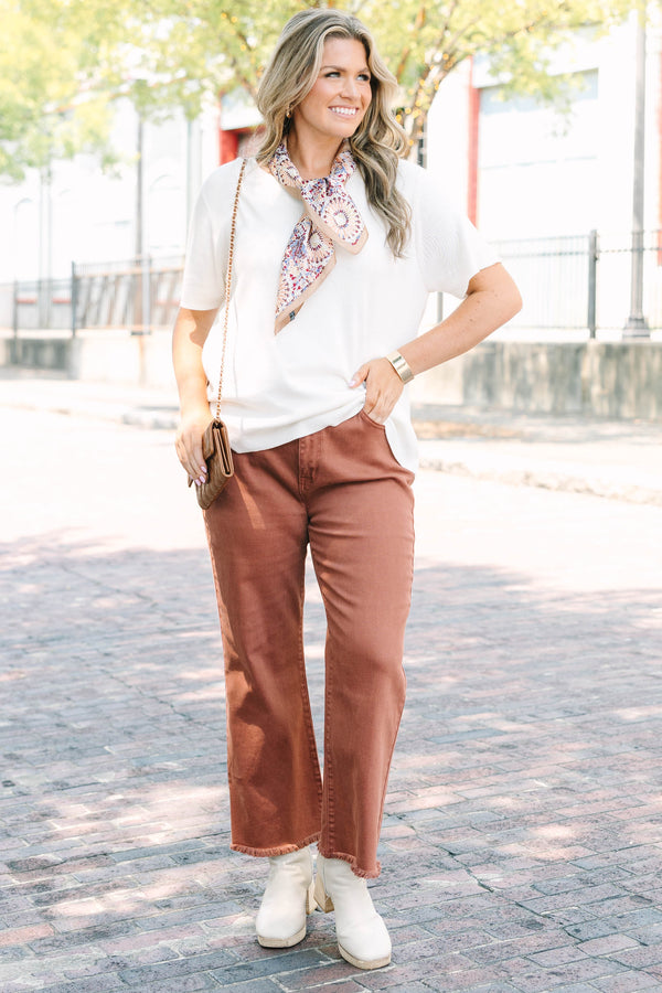 Plus Size dark rust acid-washed high-waisted boot cut jeans with a frayed hem.