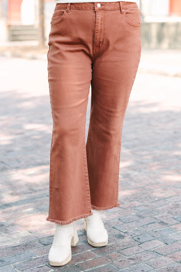 Plus Size dark rust acid-washed high-waisted boot cut jeans with a frayed hem.