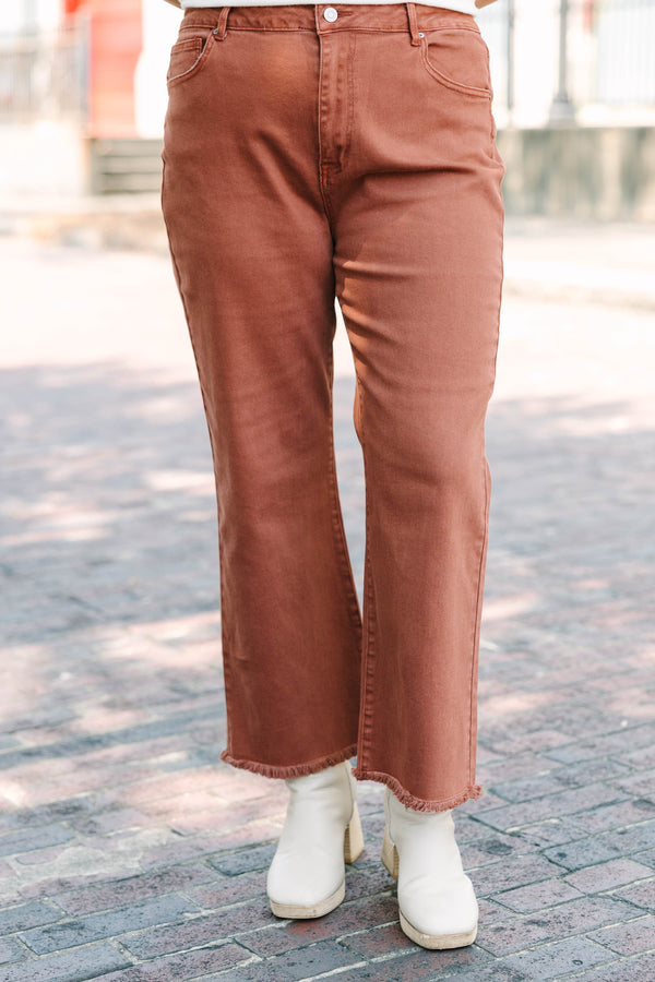 Plus Size dark rust acid-washed high-waisted boot cut jeans with a frayed hem.