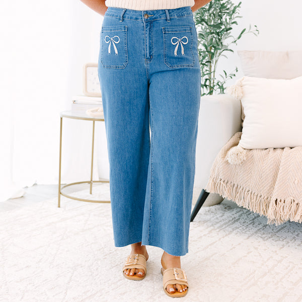Plus Size wide-leg blue jeans with front patch pockets featuring white bow embroidery.