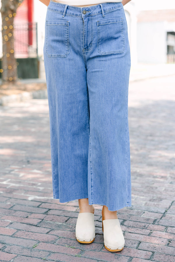 Plus Size medium wash wide leg cropped jeans with front patch pockets and a frayed hemline.