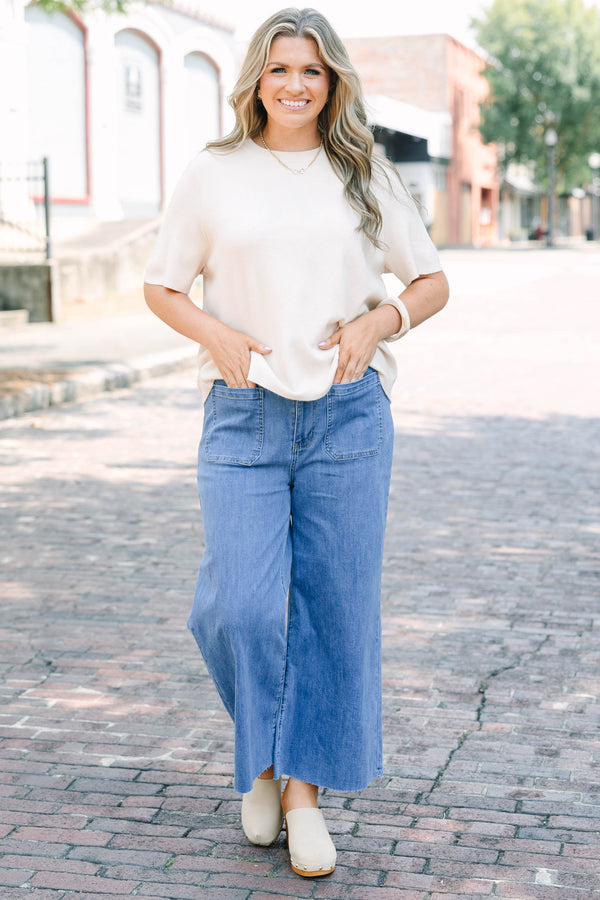 Plus Size medium wash wide leg cropped jeans with front patch pockets and a frayed hemline.