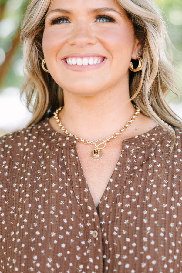 Gold chunky chain necklace with a toggle clasp and amber gemstone pendant on a plus size model.