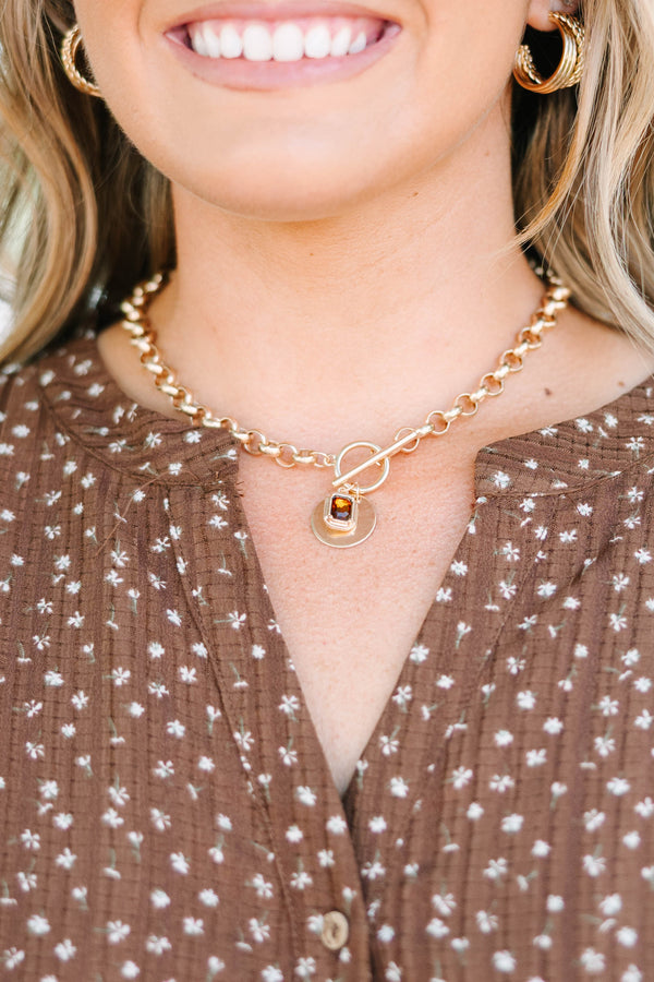 Gold chunky chain necklace with a toggle clasp and amber gemstone pendant on a plus size model.