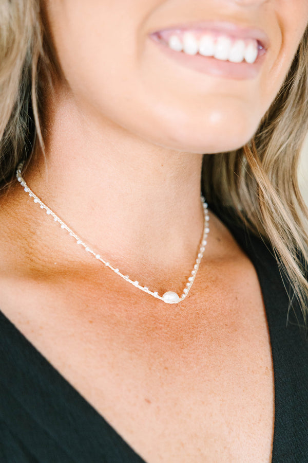Delicate gold chain necklace with small white beads and a central pearl accent.