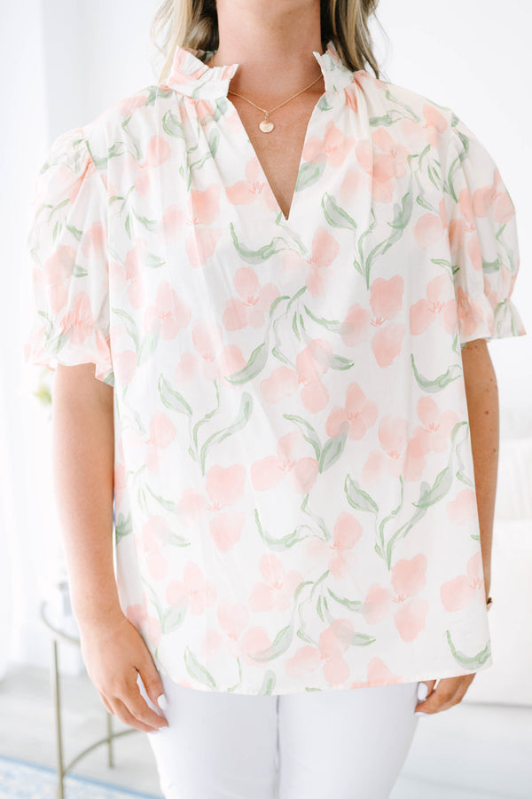 Plus Size pink floral v-neck top with short bubble sleeves and a woven straw clutch.