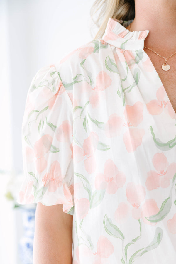Plus Size pink floral v-neck top with short bubble sleeves and a woven straw clutch.
