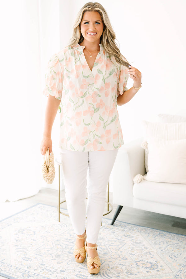 Plus Size pink floral v-neck top with short bubble sleeves and a woven straw clutch.