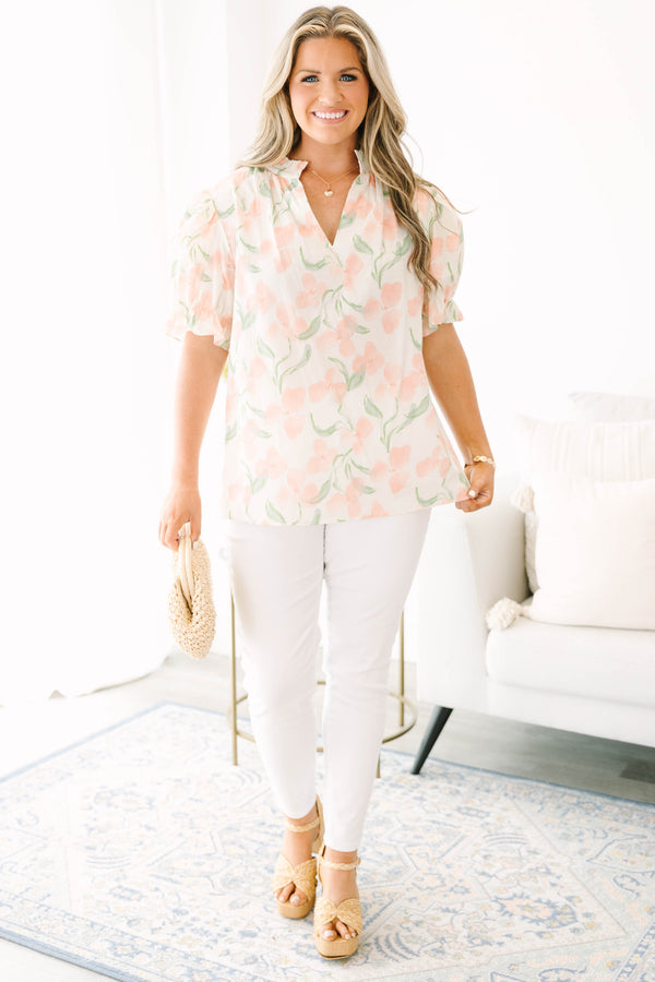 Plus Size pink floral v-neck top with short bubble sleeves and a woven straw clutch.