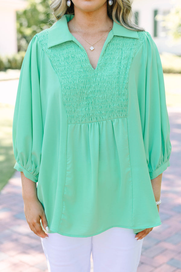 Plus size green flowy top with smocked bodice, V-neck, and balloon sleeves for a feminine fit.