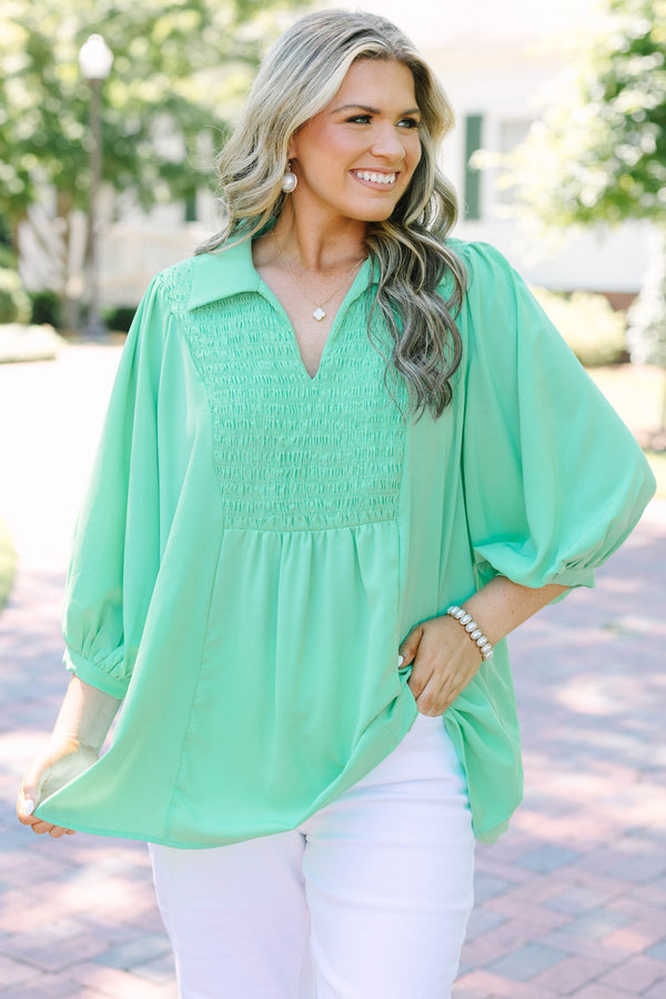 Plus size green flowy top with smocked bodice, V-neck, and balloon sleeves for a feminine fit.