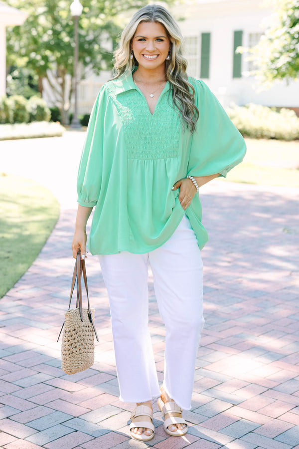 Plus size green flowy top with smocked bodice, V-neck, and balloon sleeves for a feminine fit.