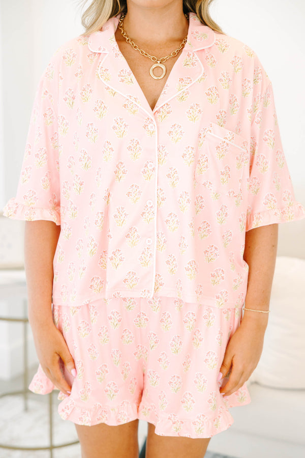 Plus Size pink block print pajama set with short sleeves, button-down top, and ruffled shorts.