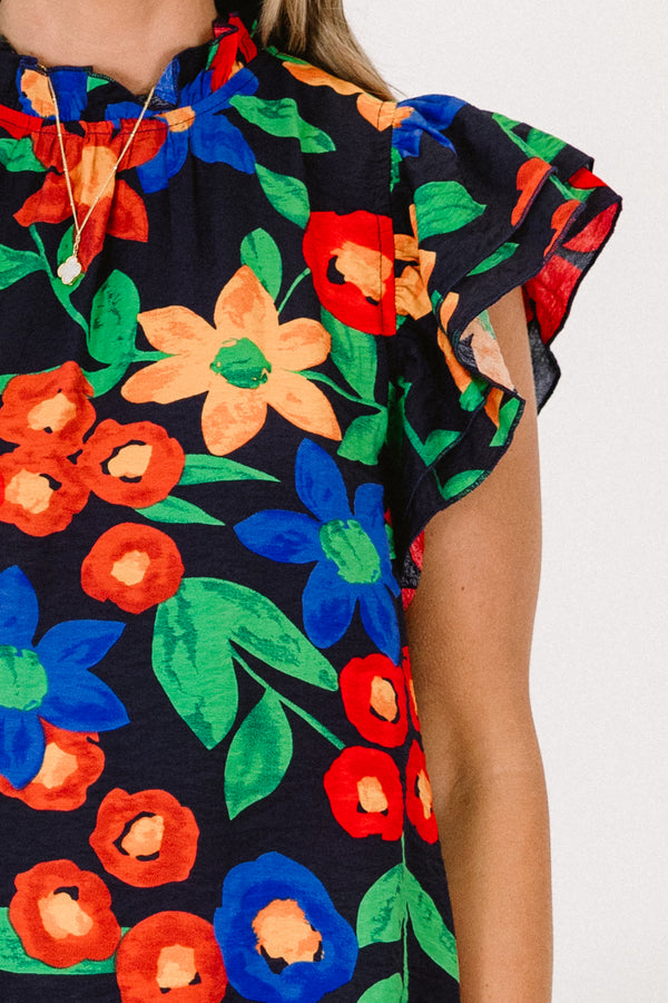 Plus Size navy floral top with flutter sleeves, a ruffled neckline, and colorful flower patterns.