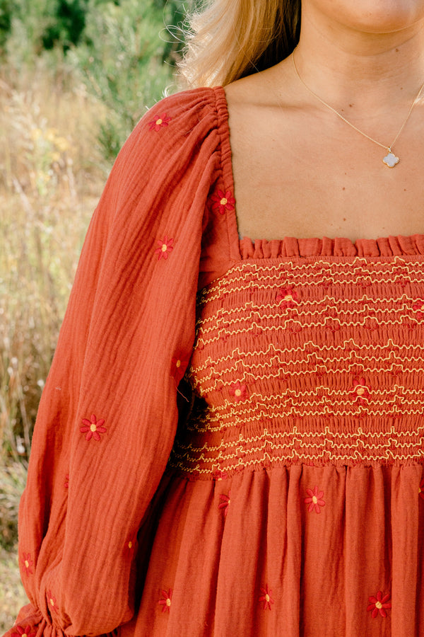 Chic Soul plus size clothing, rust orange long sleeve maxi dress with tiered skirt, embroidered dark orange flowers, and light yellow and orange stitching through stretchy top