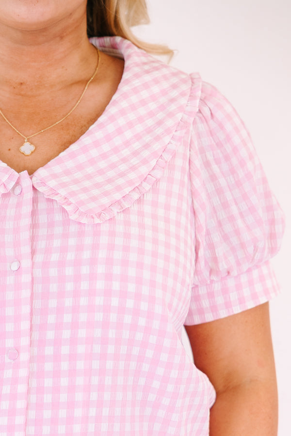 Chic Soul plus size clothing, pink button up top with short sleeves that have cuffs at the end of the sleeves as well as a bib detail on the shoulders that has ruffle detailing and a pink gingham pattern throughout 
