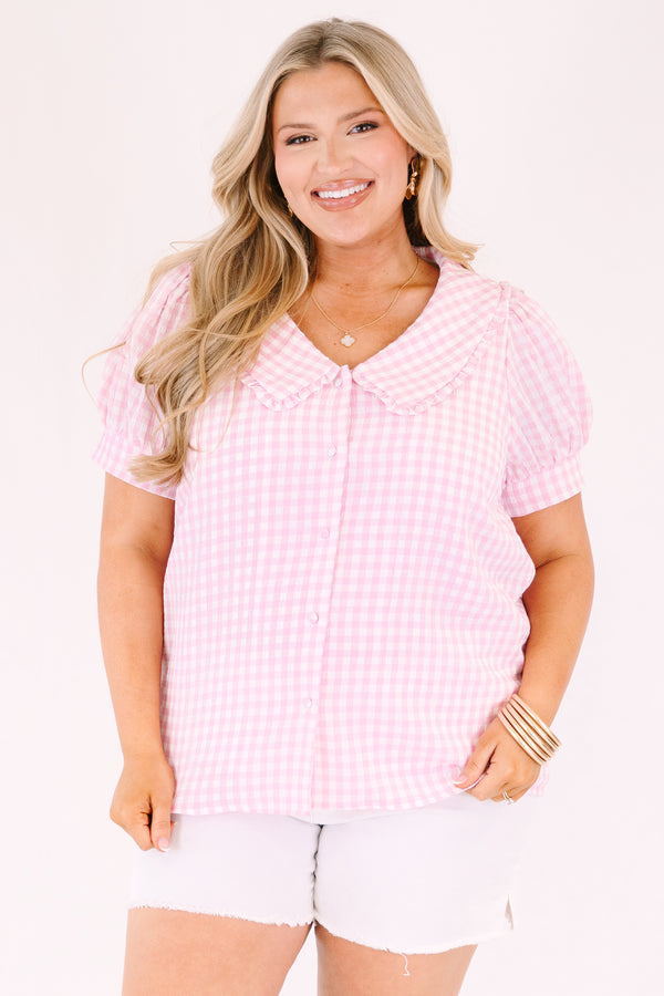 Chic Soul plus size clothing, pink button up top with short sleeves that have cuffs at the end of the sleeves as well as a bib detail on the shoulders that has ruffle detailing and a pink gingham pattern throughout 
