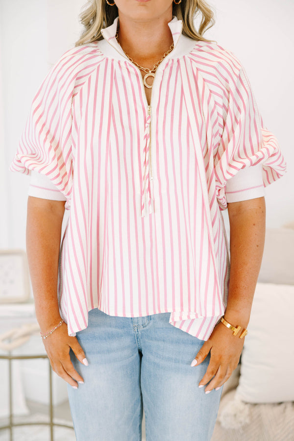 Plus size woman in a pink and white striped flowy top with a quarter-zip and puff sleeves.