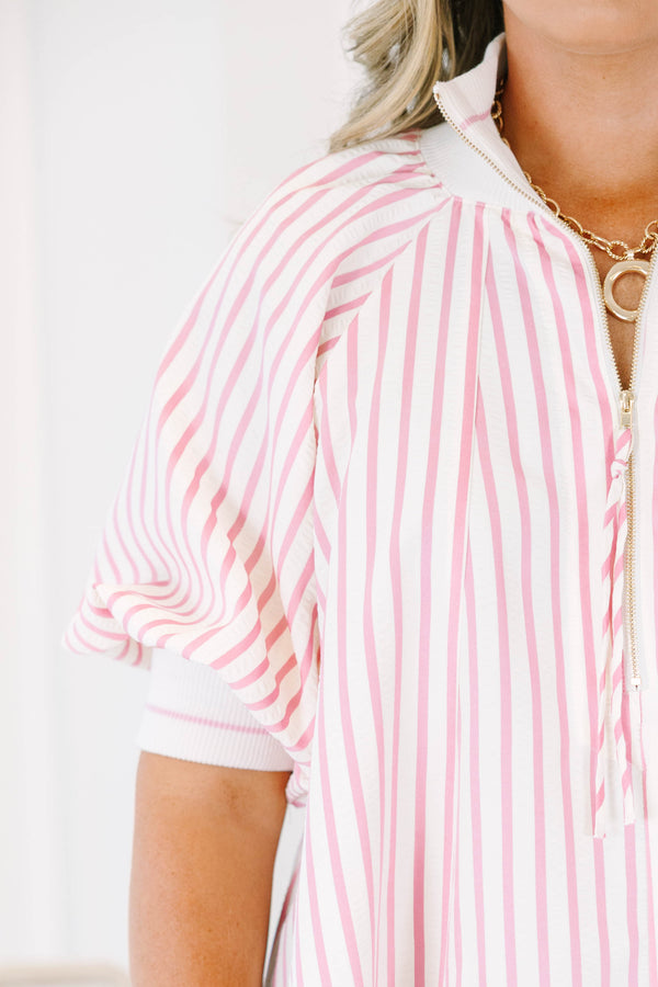 Plus size woman in a pink and white striped flowy top with a quarter-zip and puff sleeves.