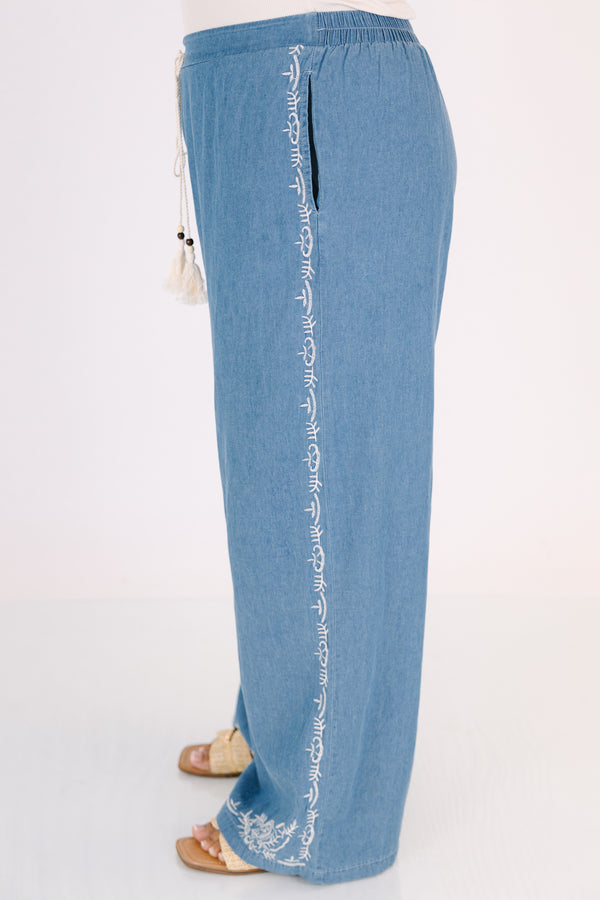 Chic Soul plus size clothing, medium wash denim blue straight leg flowy pants with white embroidery detailing on the ankles and white drawstring tassel tie at the waist
