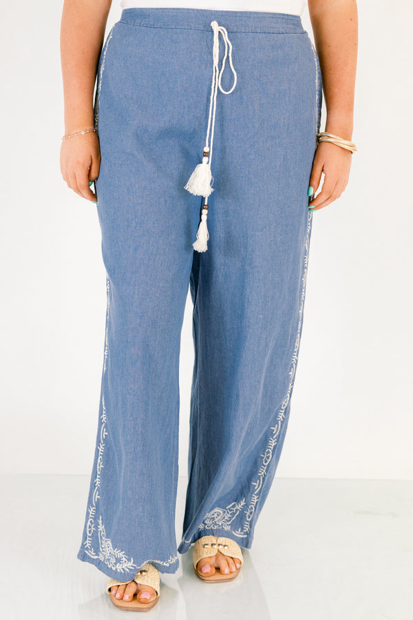 Chic Soul plus size clothing, medium wash denim blue straight leg flowy pants with white embroidery detailing on the ankles and white drawstring tassel tie at the waist