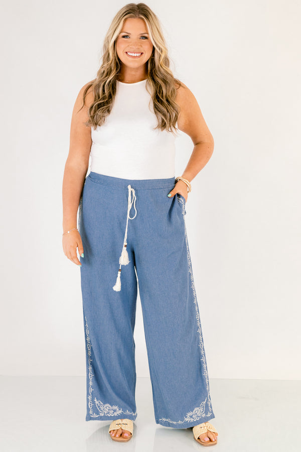 Chic Soul plus size clothing, medium wash denim blue straight leg flowy pants with white embroidery detailing on the ankles and white drawstring tassel tie at the waist