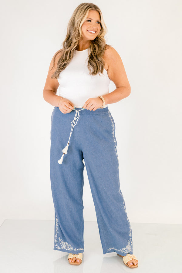 Chic Soul plus size clothing, medium wash denim blue straight leg flowy pants with white embroidery detailing on the ankles and white drawstring tassel tie at the waist
