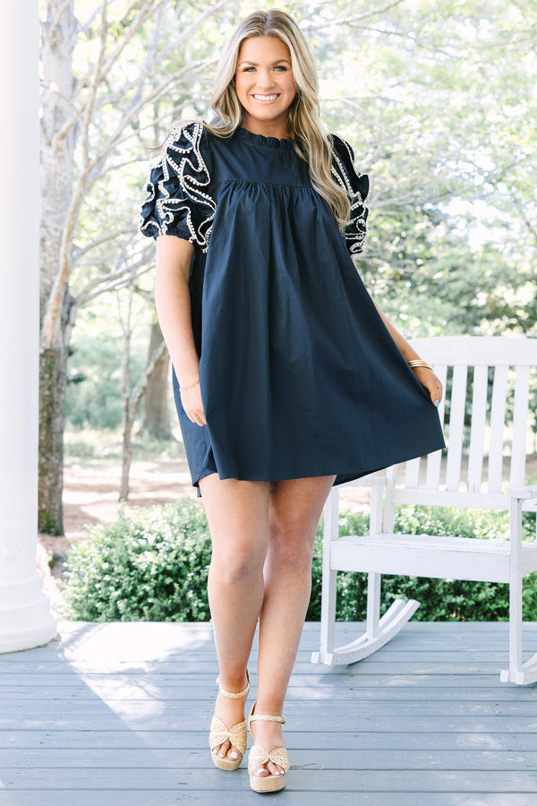 Navy cotton mini dress with ruffled high neck and tiered puff sleeves featuring white embroidery.