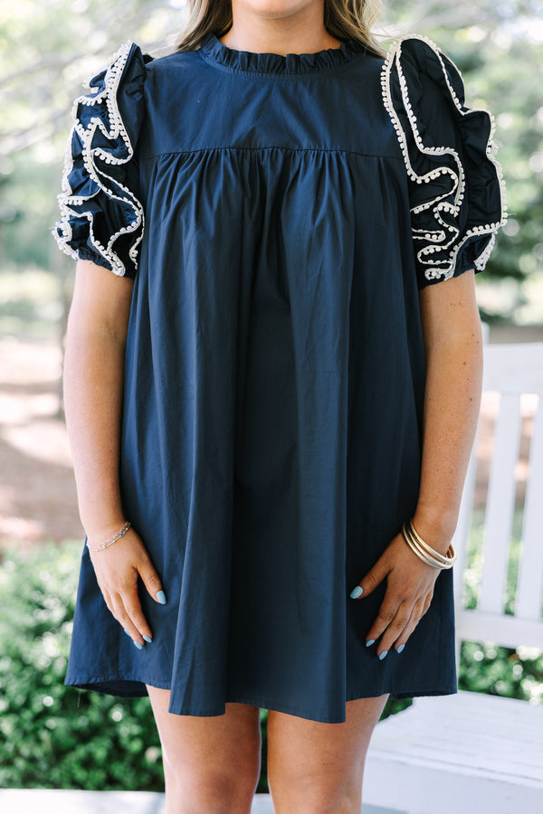Navy cotton mini dress with a high ruffled neckline and tiered ruffle sleeves with white trim.