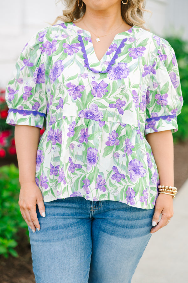 Chic Soul plus size clothing, a purple, green, and white floral peplum style top feature a puff sleeve and a notch style V-neck collar. There is contrasting purple scallop trim on the sleeves and collar