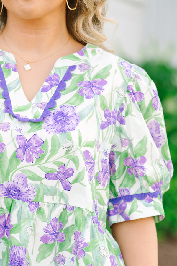 Chic Soul plus size clothing, a purple, green, and white floral peplum style top feature a puff sleeve and a notch style V-neck collar. There is contrasting purple scallop trim on the sleeves and collar