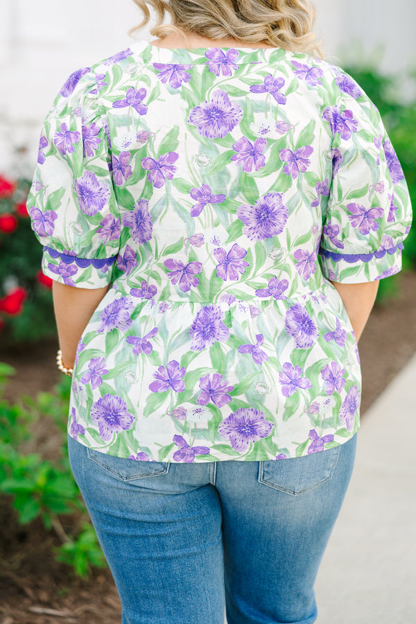 Chic Soul plus size clothing, a purple, green, and white floral peplum style top feature a puff sleeve and a notch style V-neck collar. There is contrasting purple scallop trim on the sleeves and collar