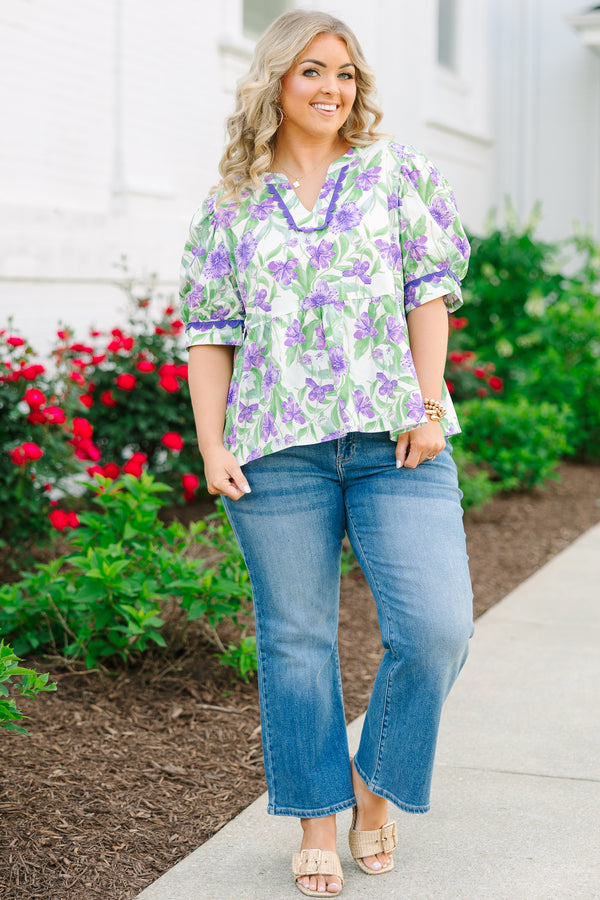 Chic Soul plus size clothing, a purple, green, and white floral peplum style top feature a puff sleeve and a notch style V-neck collar. There is contrasting purple scallop trim on the sleeves and collar