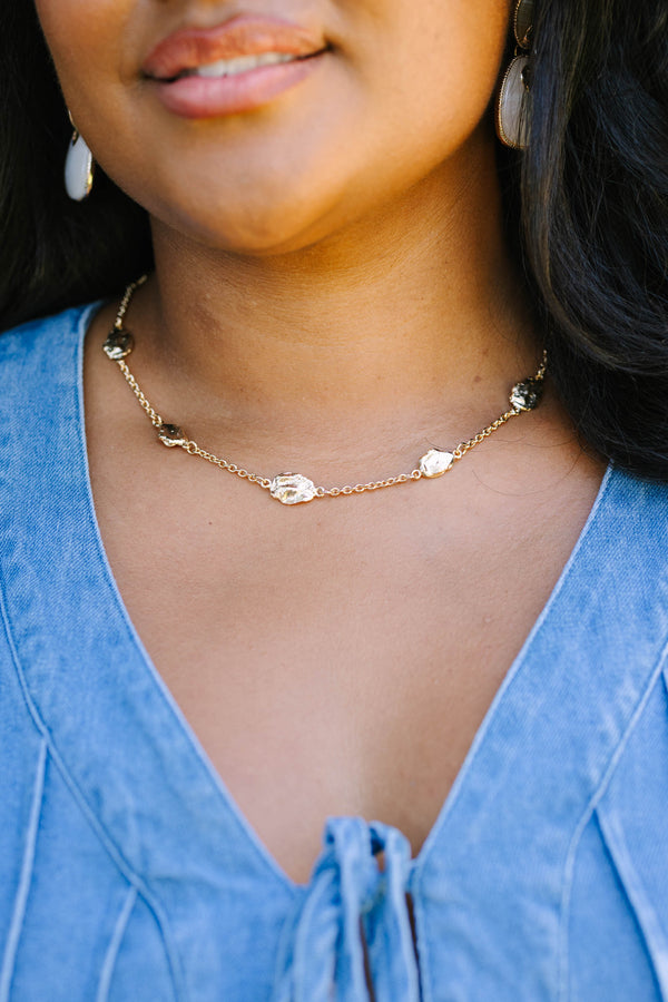Gold necklace with organic-shaped metal charms.
